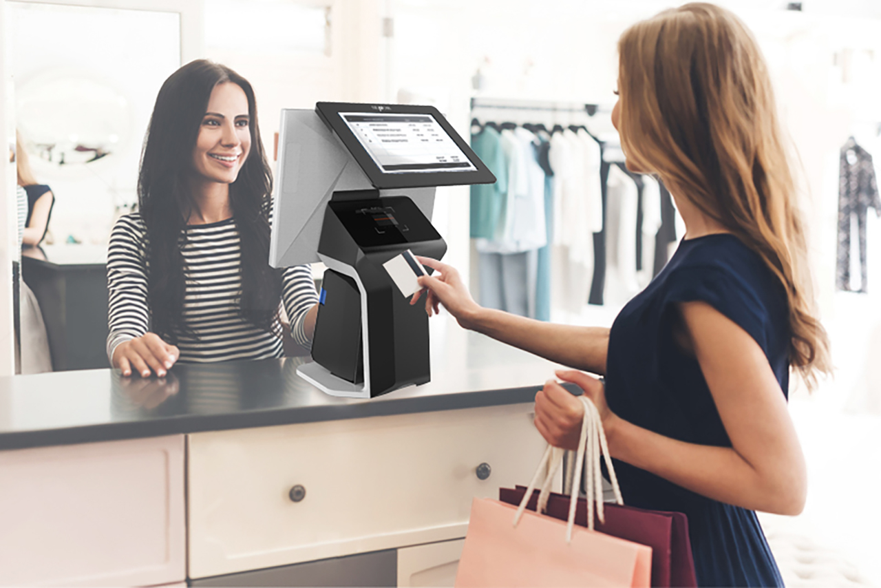 SENOR_A smiling waitress in a clothing store stands in front of a AIO Touch POS terminals and a customer pays by credit card